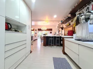Ambiente interno de uma sala de estar com armários brancos e piso de madeira clara.