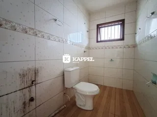 Banheiro com revestimento de azulejos brancos e piso de madeira.