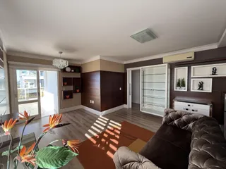 Sala de estar com piso de madeira e vista externa através de portas de vidro.