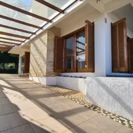 Foto de uma área externa coberta com estrutura de madeira e piso de cerâmica.