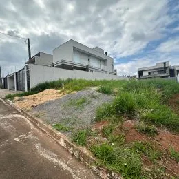 Vista externa de uma propriedade com terreno em construção e vegetação rasteira.