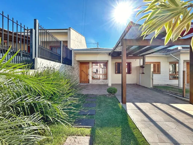 Vista externa de uma residência com jardim e cerca de metal.