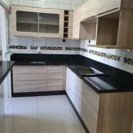 Foto de uma cozinha com armários de madeira clara e bancada escura.