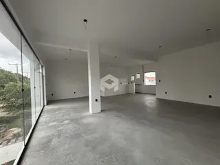 Interior de um espaço amplo com piso de concreto e paredes brancas.