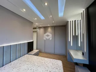 Quarto moderno com cabeceira estofada e armários embutidos.