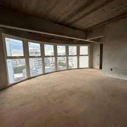 Ambiente interno amplo com grandes janelas e teto exposto.