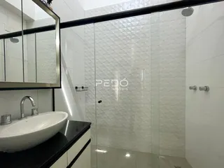 Foto de um banheiro com box de vidro e revestimento branco.