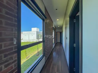 Vista de um corredor interno com vista para o exterior de uma residência.