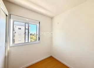 Interior de um cômodo com parede branca e piso de madeira clara.
