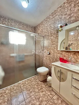 Foto de um banheiro com box de vidro e piso de cerâmica.