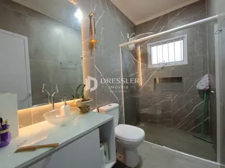 Banheiro com box de vidro e revestimento de parede em tons de cinza.