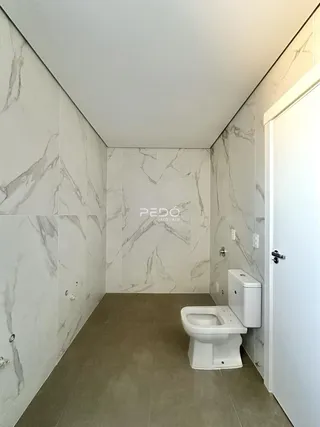 O interior de um banheiro com revestimento em mármore claro e piso de cerâmica.