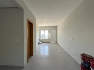 Vista do corredor interno de uma residência com paredes brancas e piso de cerâmica.