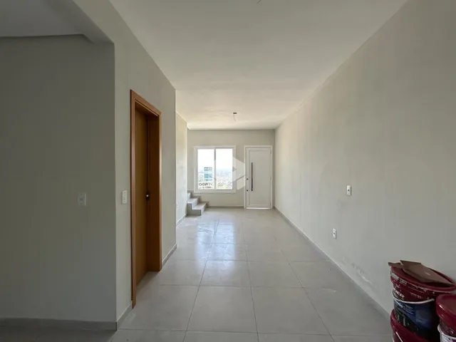 Vista do corredor interno de uma residência com paredes brancas e piso de cerâmica.