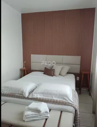 Quarto com cama grande e cabeceira em ambiente interno.