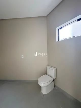 Uma parede clara com um vaso sanitário em um ambiente interno.