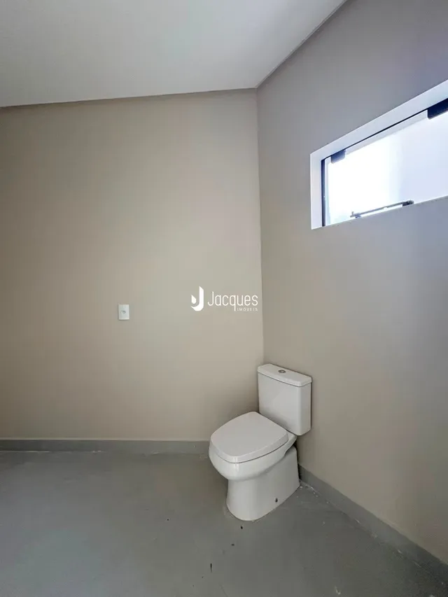 Uma parede clara com um vaso sanitário em um ambiente interno.