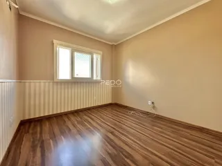 Ambiente interno com piso de madeira e parede de painel na residência.