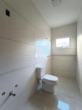 Banheiro com revestimento branco e piso claro.