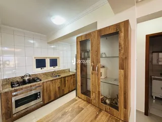 Vista interna de uma cozinha com armários de madeira e piso de madeira.