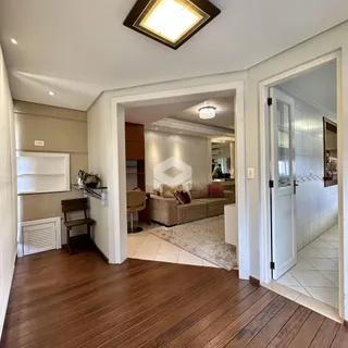 Hall de entrada com piso de madeira e vista para a sala de estar.