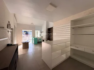 Interior de uma sala de estar com piso de cerâmica clara e armários brancos.
