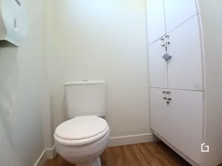 Foto de um banheiro com azulejos brancos e piso de madeira.