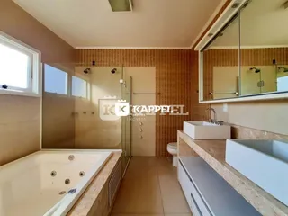 Foto de um banheiro com banheira e box de vidro em um imóvel.