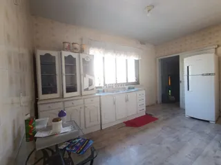 Interior de uma cozinha com armários brancos e janela em Lajeado.