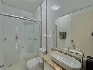 Banheiro moderno com box de vidro e revestimento cerâmico.