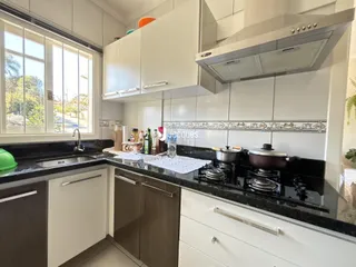Foto de uma cozinha moderna com armários brancos e bancadas escuras.