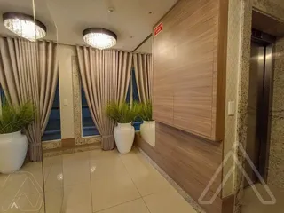 Foto interna de uma sala com piso de cerâmica e cortinas claras.