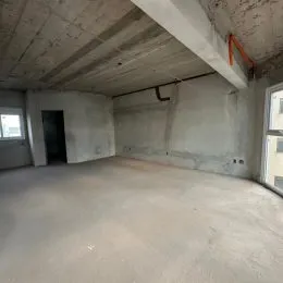 Espaço interno amplo com paredes de concreto aparente e piso de cimento.