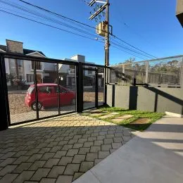 Foto da área externa pavimentada com piso de tijolos e grade de vidro.