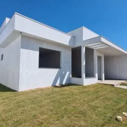 Foto da fachada de uma casa branca com jardim em Lajeado, Brasil.