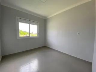 Ambiente interno com paredes brancas e piso claro, mostrando uma janela.