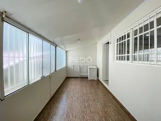 Corredor interno de um imóvel com piso de cerâmica e grandes janelas.