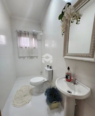 Um banheiro com revestimento cerâmico branco e louças brancas.