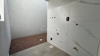 Hall de passagem com parede branca e piso de cascalho marrom.