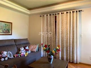 Sala de estar com sofá marrom e cortinas claras.