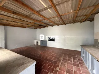 Foto de um ambiente interno com piso de tijolos aparentes e estrutura de teto exposta.