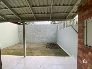 Vista externa de um pátio com paredes brancas e piso de cerâmica.