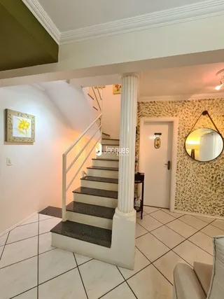 Hall de entrada com escadaria e parede clara em uma residência.