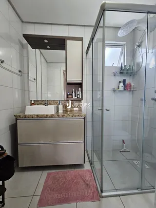 Foto de um banheiro com box de vidro e bancada de mármore.