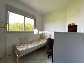 Quarto com janela grande e vista para a vegetação externa.