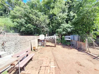 Vista externa de um terreno com terra e cerca de madeira.