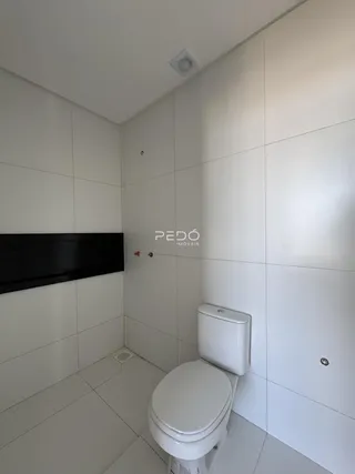 Um banheiro com revestimento branco e piso claro.