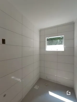 Corredor interno com paredes brancas e piso cinza claro.