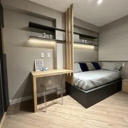 Quarto com cama e estantes de parede em um apartamento.