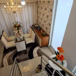 Sala de estar com sofá e cortinas claras em um apartamento.